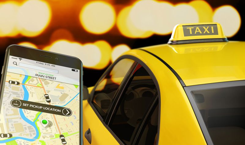 App auf einem Handy und ein Taxi